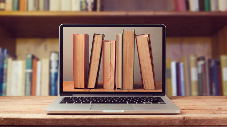 Pc skjerm som viser bilde av bøker med bokhyller i bakgrunnen