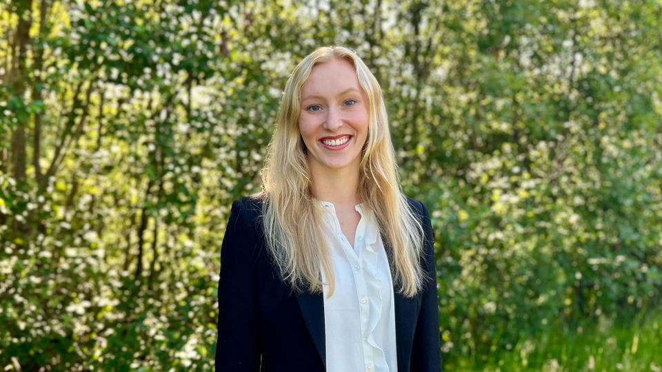 Solveig Gundersen Vik, ein person med langt blondt hår, kledd i mørk blazer og kvit skjorte. Solveig smiler til kameraet.