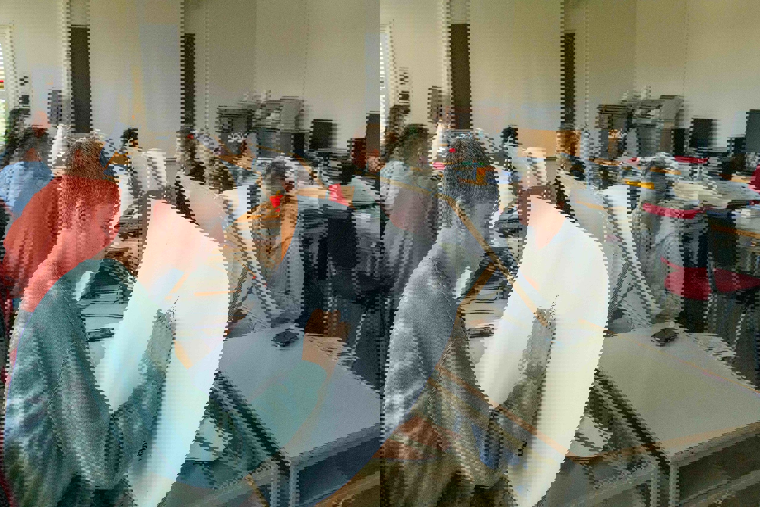 Ein gjeng studentar sit i eit klasserom og teiknar på store ark.