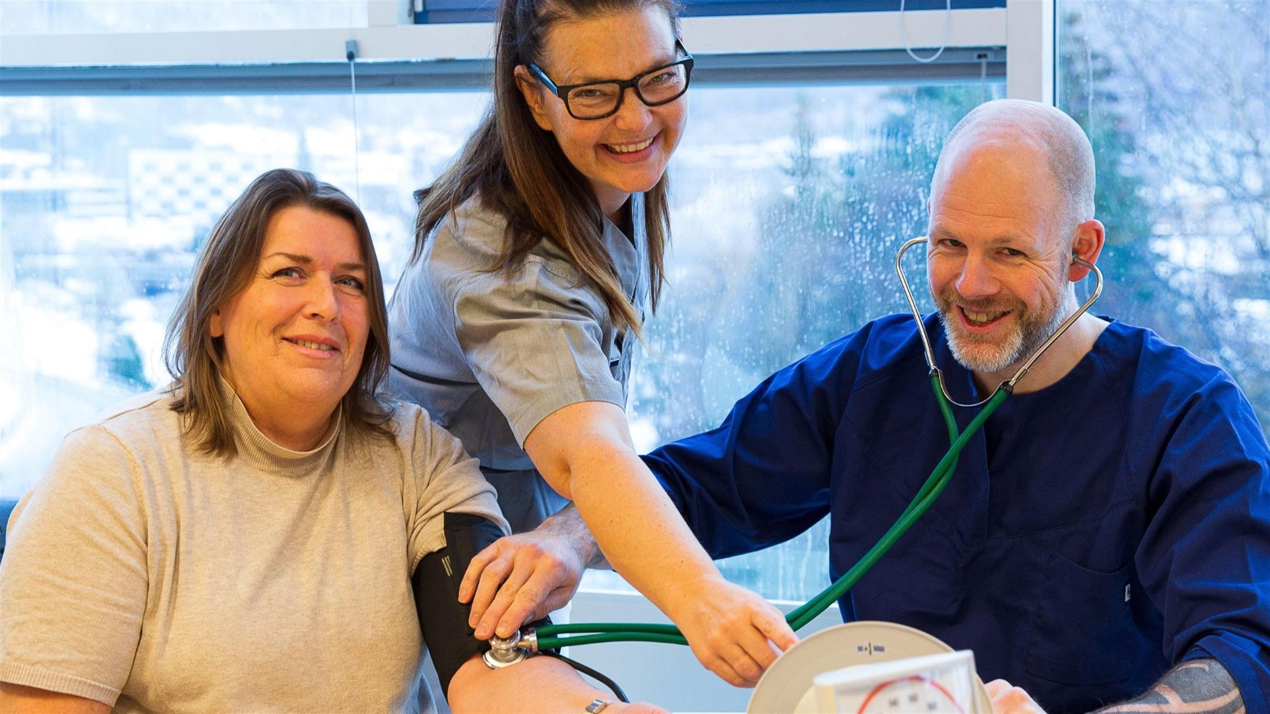 Vernepleier og vernepleierstudent måler blodtrykk på kvinne
