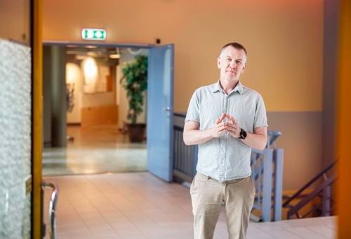 Christian Moltu står i ein korridor, ser inn i kamera. Hendene framfor seg med fingrane mot kvarandre, ser tenksom ut.
