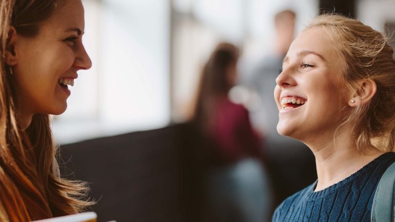 To smilende jenter ser på hverandre