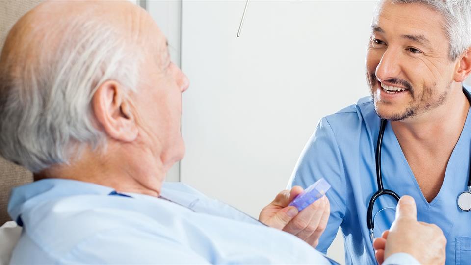 En sykepleier i samtale med en eldre mannlig pasient.