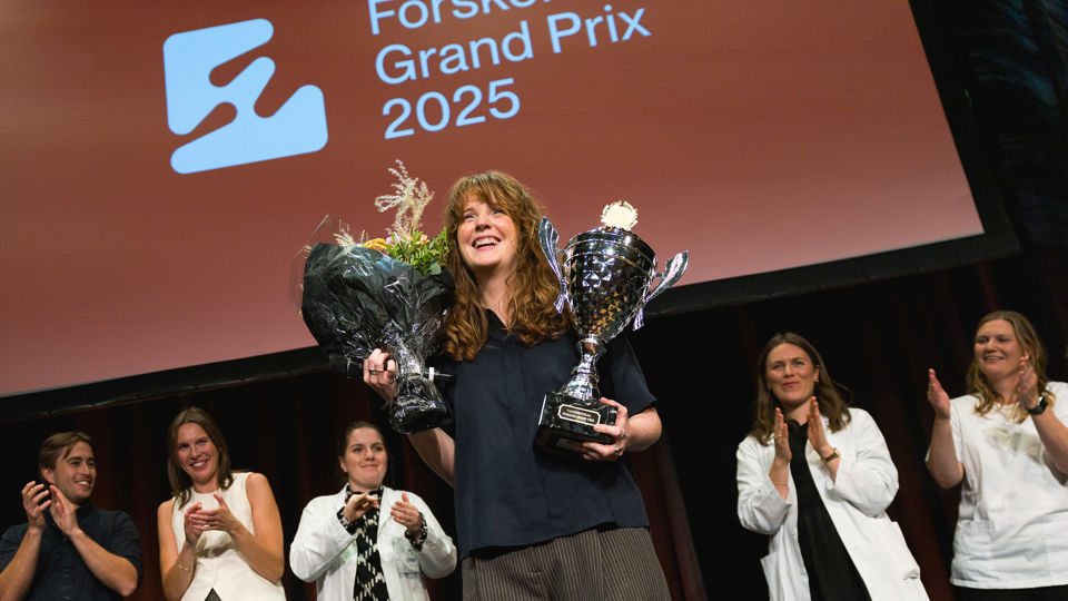 Vinneren av Forsker Grand Prix 2025 hever pokalen. 