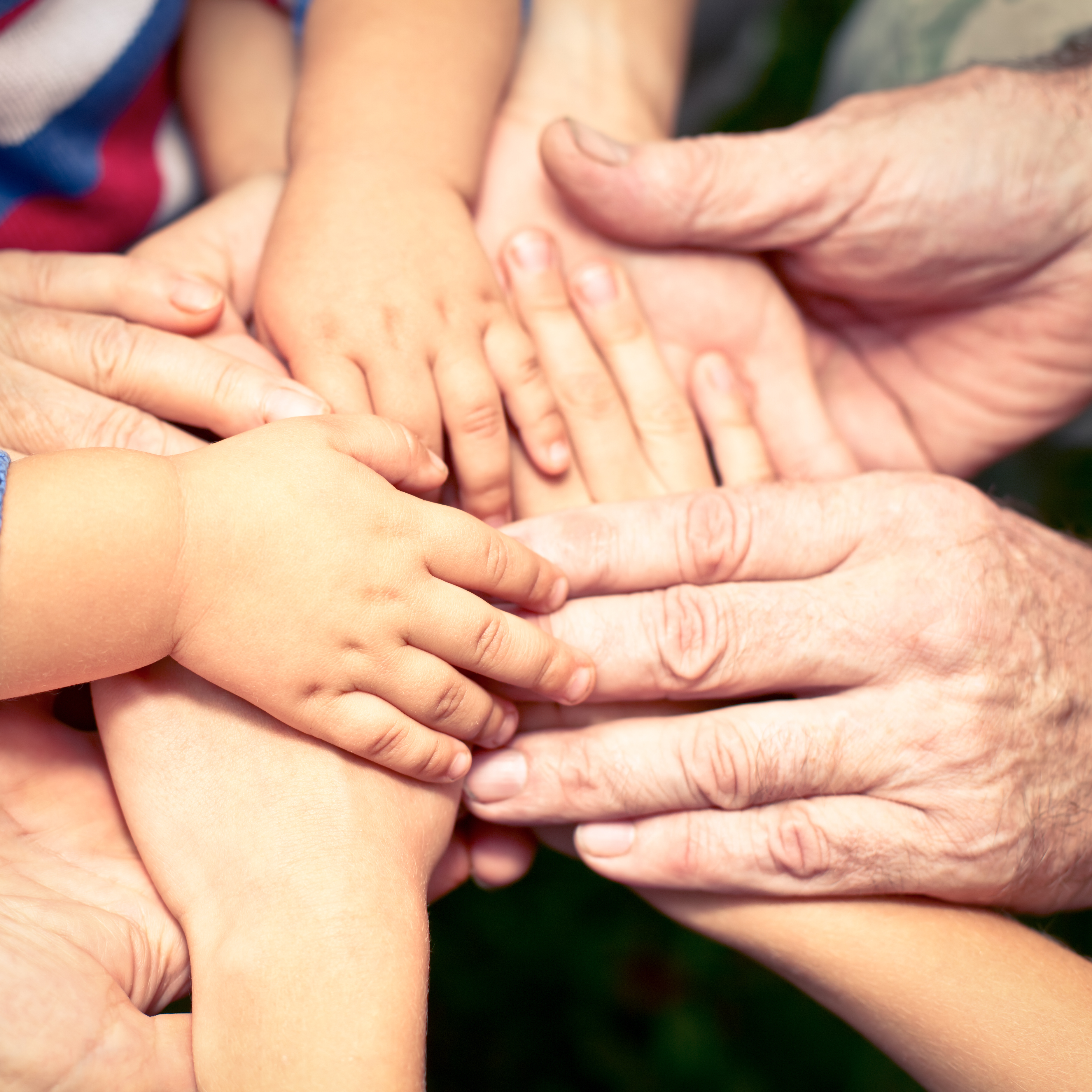 Mange hender som er lagt over kvarandre. Hendene tilhøyrer tydeleg folk av ulik alder, frå barn til eldre.