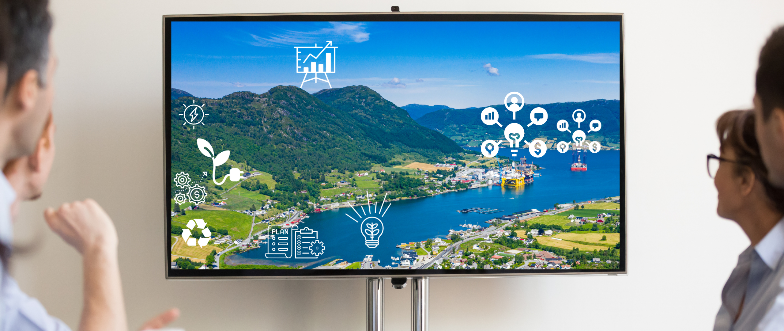 Personer i en gruppe ser på en skjerm. På skjermen er det bilde av et landskap i Rogaland og ulike symboler for bærekraft, kommunikasjon og ledelse. 