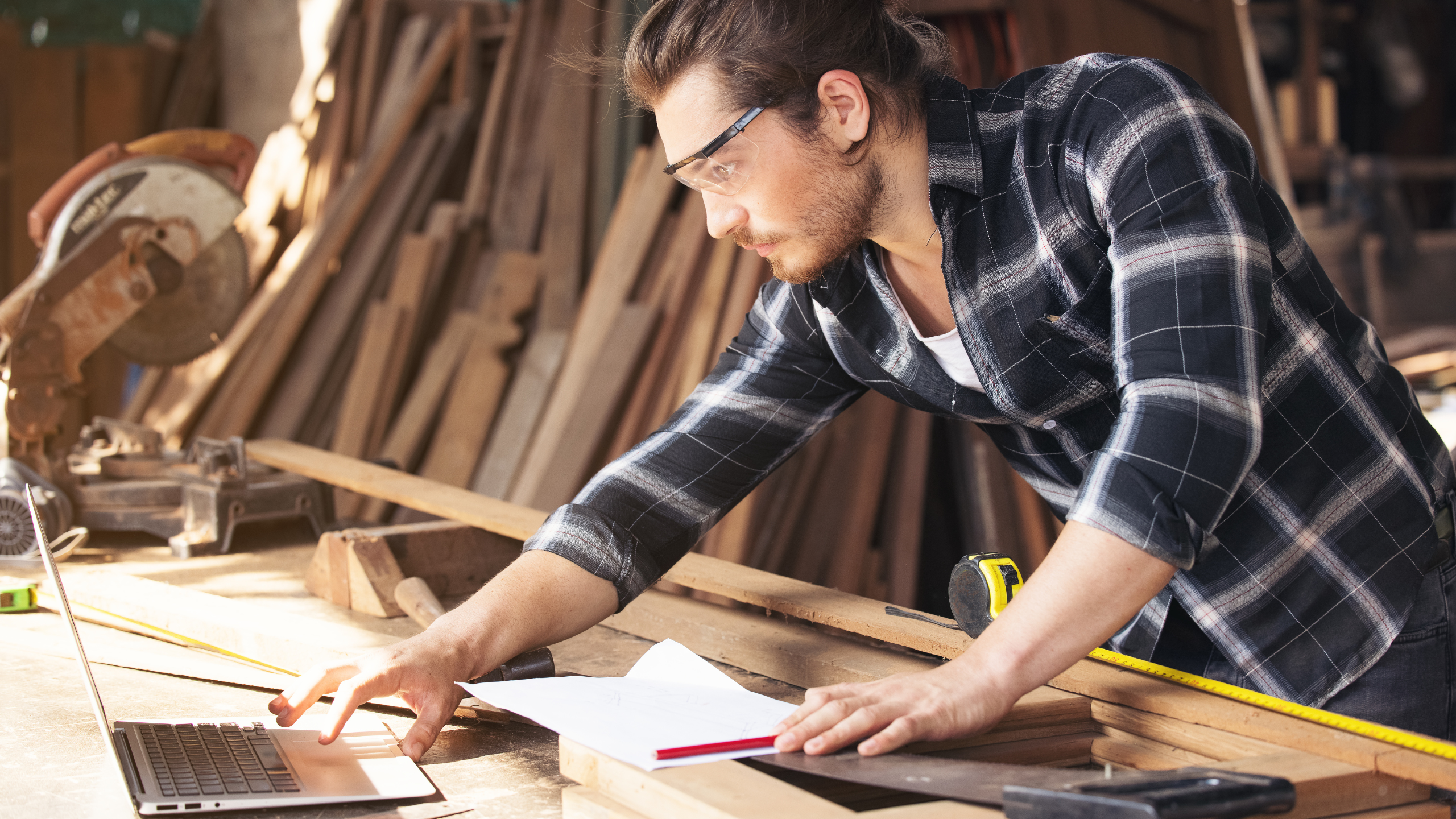 Mann med vernebriller og verktøy ser på pc. 