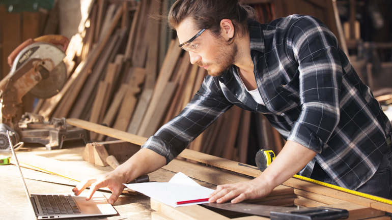 Mann med vernebriller og verktøy ser på pc. 