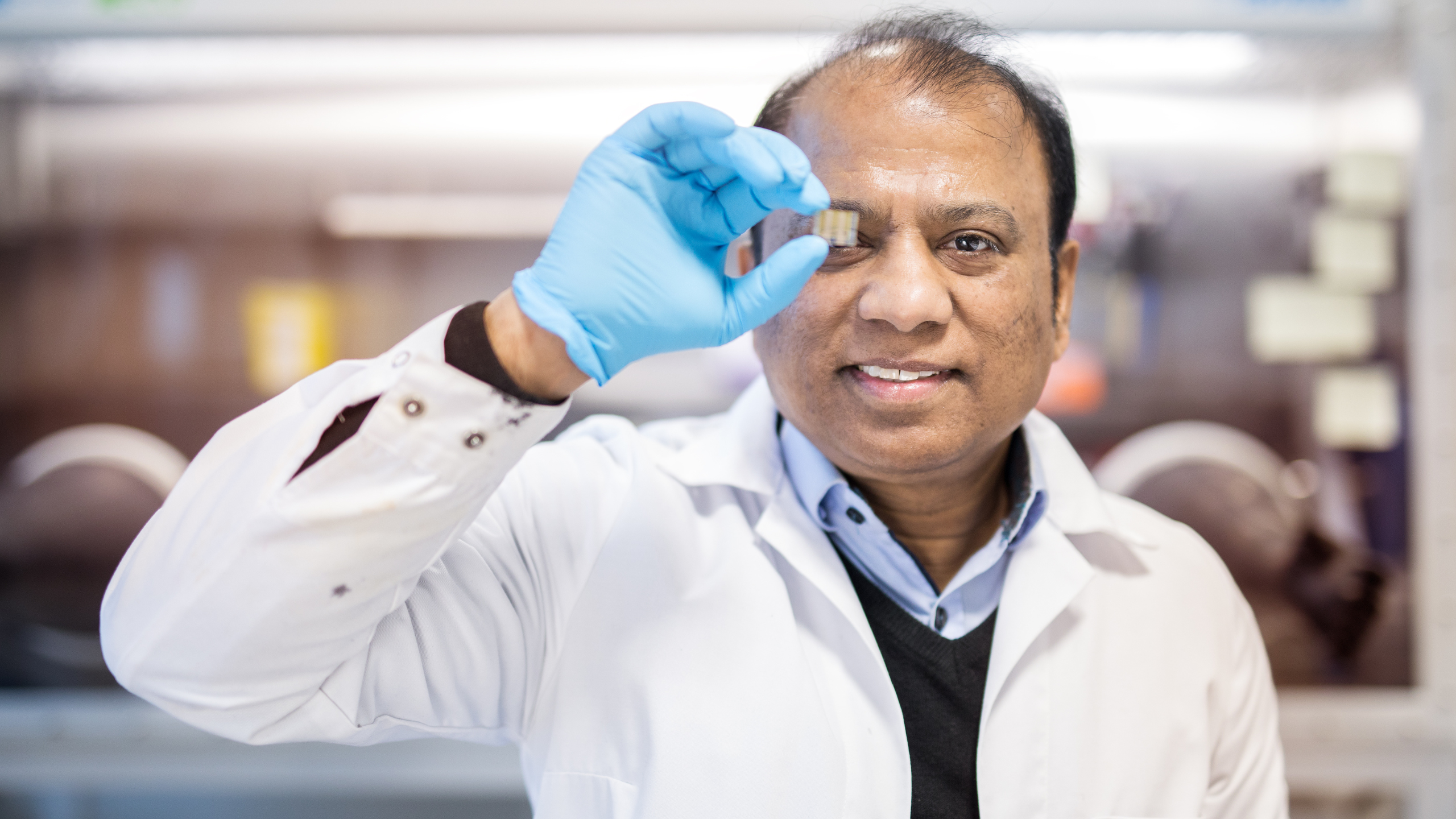 Mann i hvit frakk holder en liten nanopartikkel