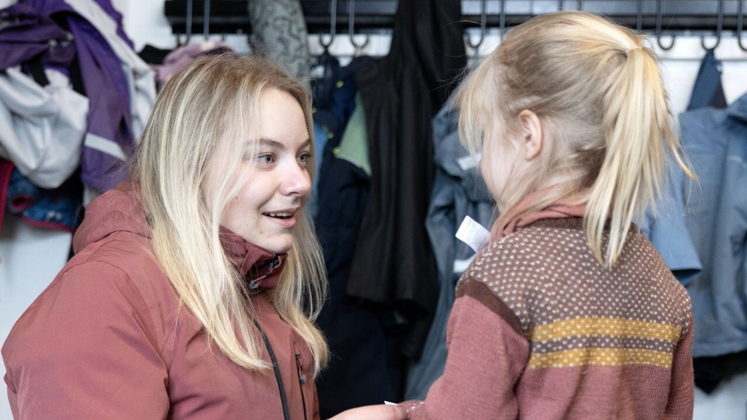 Barnehageansatt som hjelper barn med påkledning