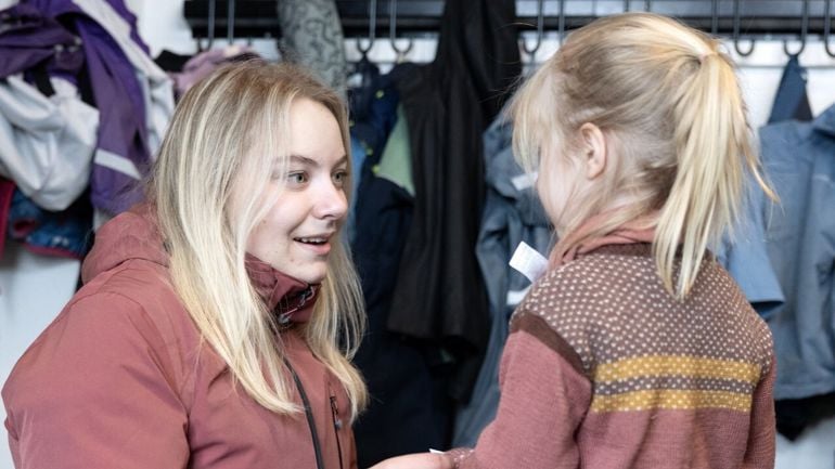 Barnehageansatt som hjelper barn med påkledning