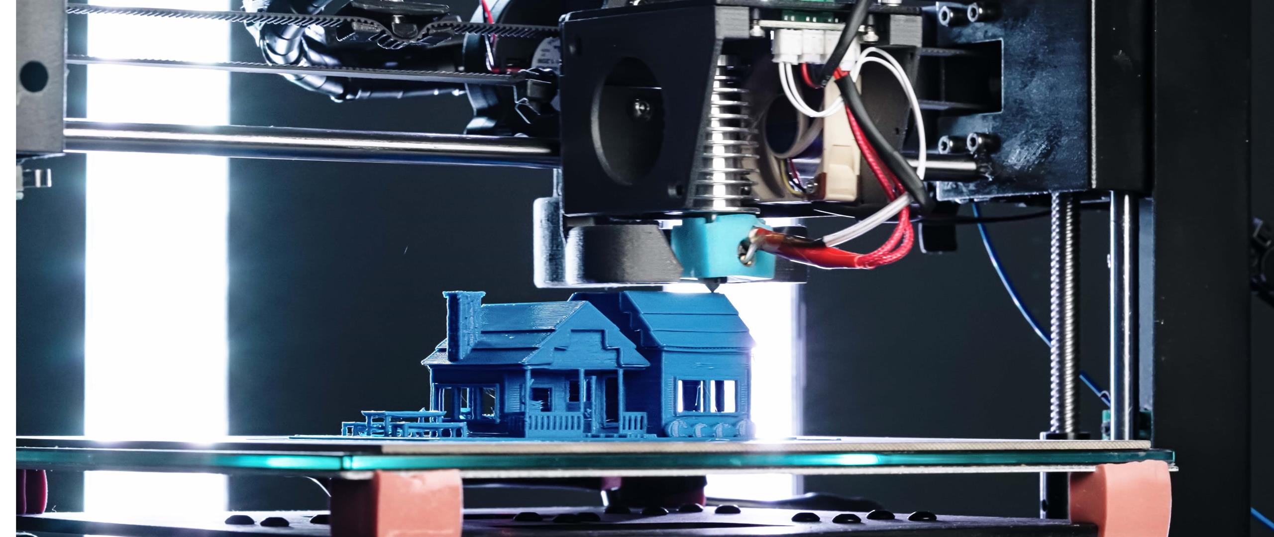 3D printer som printer et blått lite hus