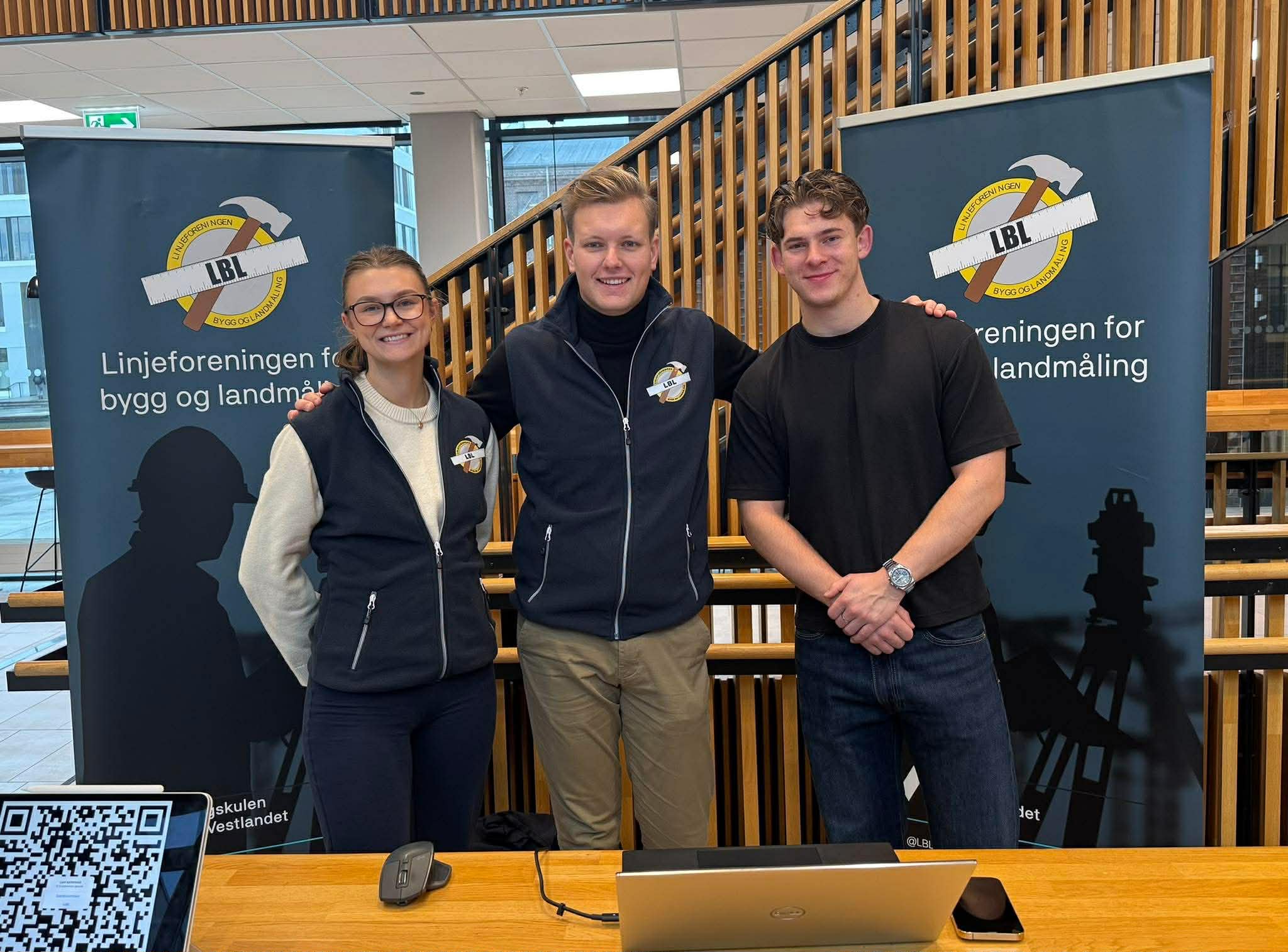 Tre studentar på stand. Messevegg i bakgrunnen.