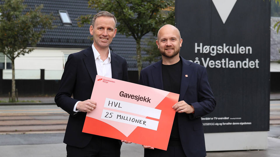 Frode Nergaard Fjeldstad ved Agenda Vestlandet overrekker gavesjekk på 25 millioner kroner til Øyvind Berge ved Høgskulen på Vestlandet.