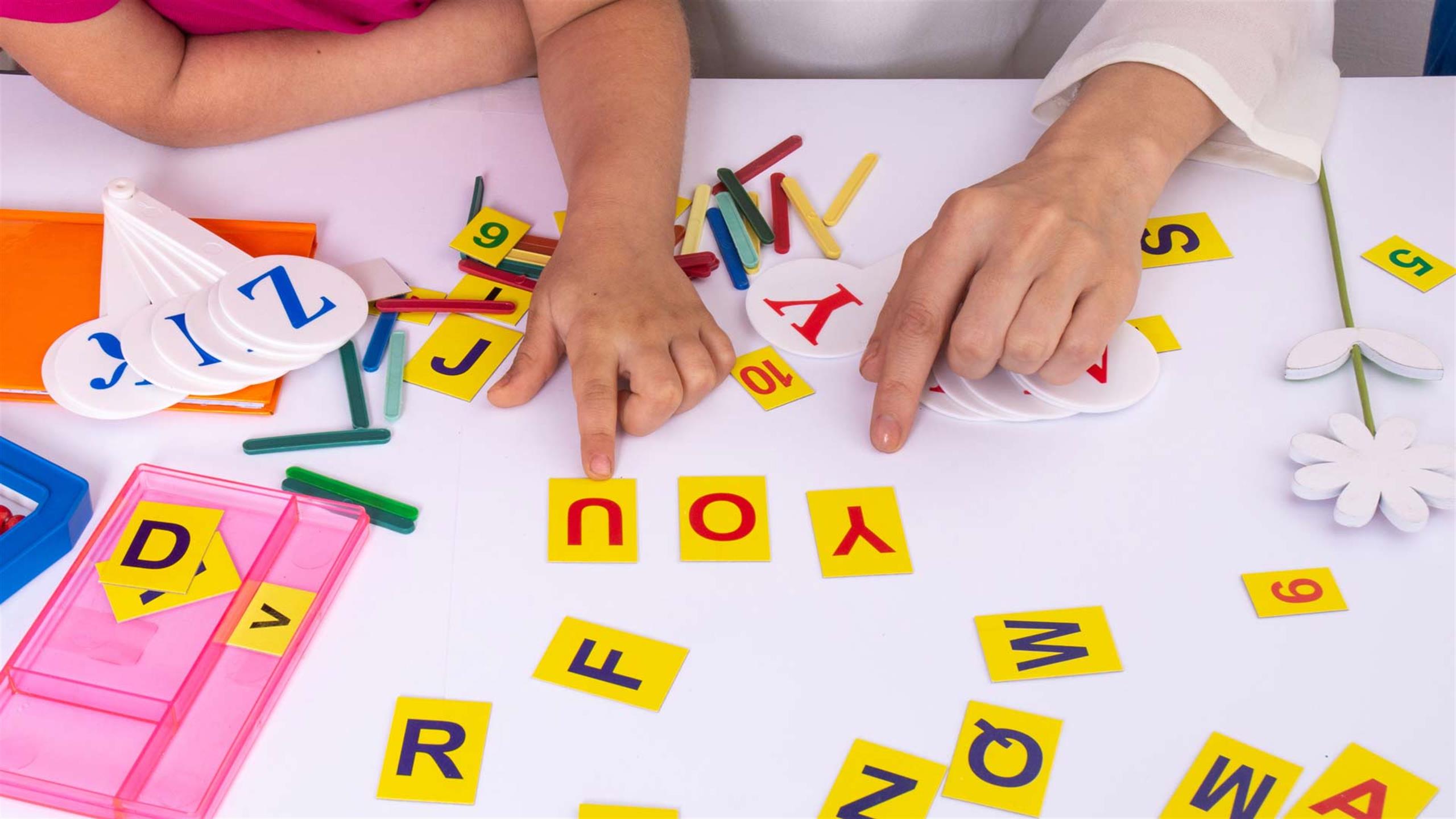 Two hands pointing at some letters at the table.