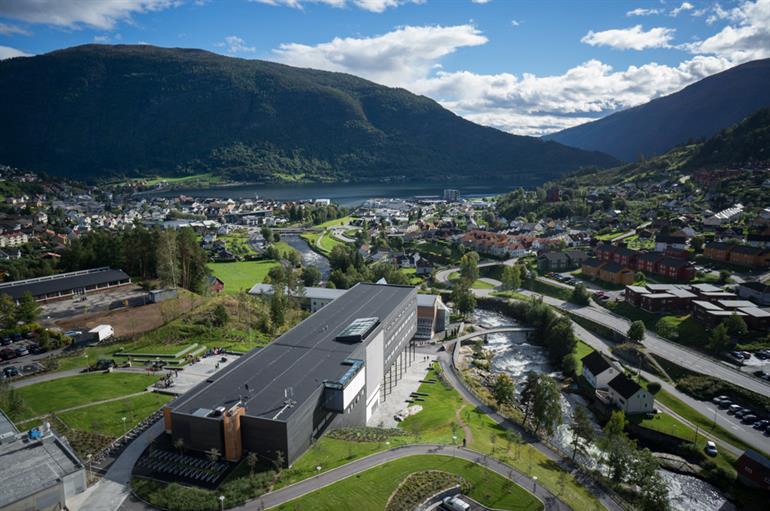 Dronebilde over campus og Sogndal, med bygningar, fjell og fjord. 