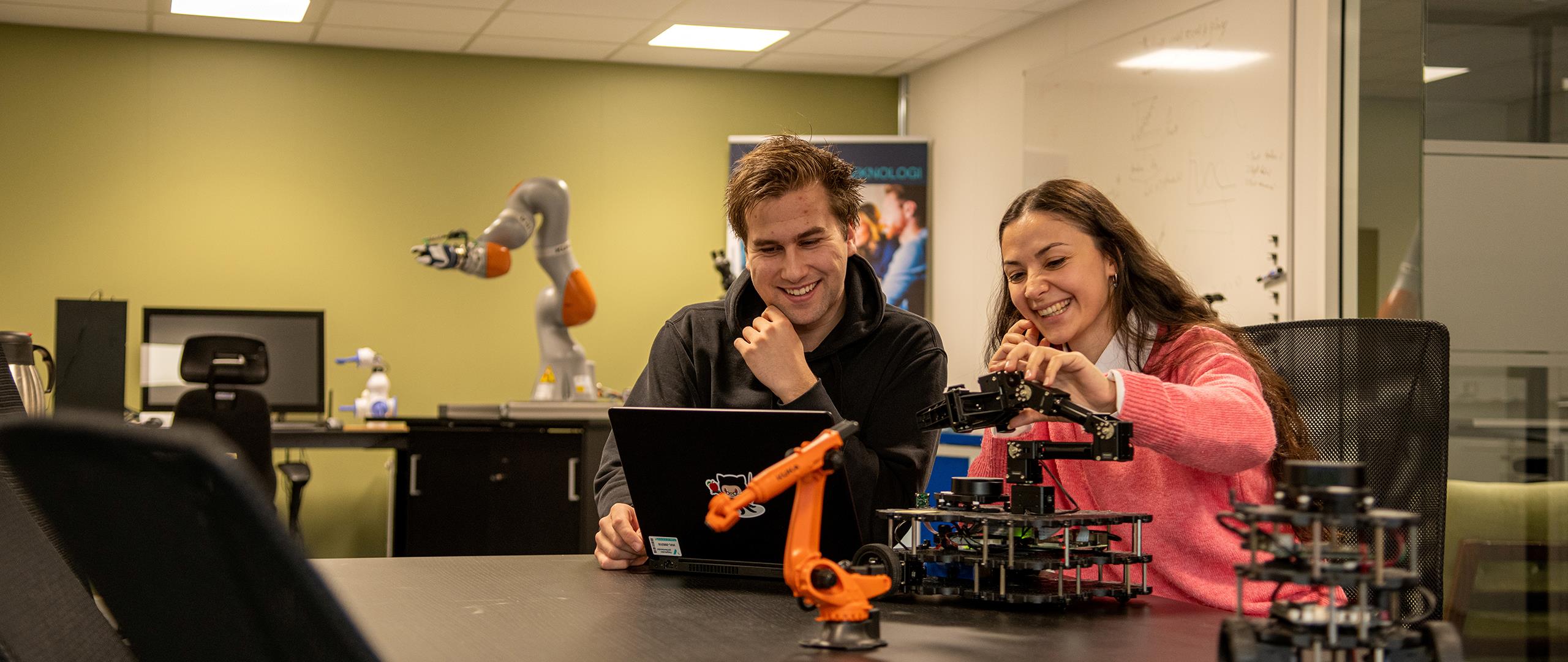 Blide ingeniørstudentar jobbar med robotløysingar (foto)