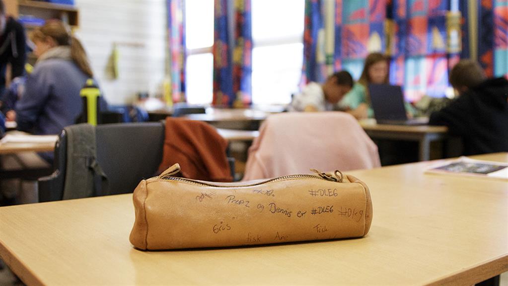 Skinnpennal på skolepult i et klasserom. 