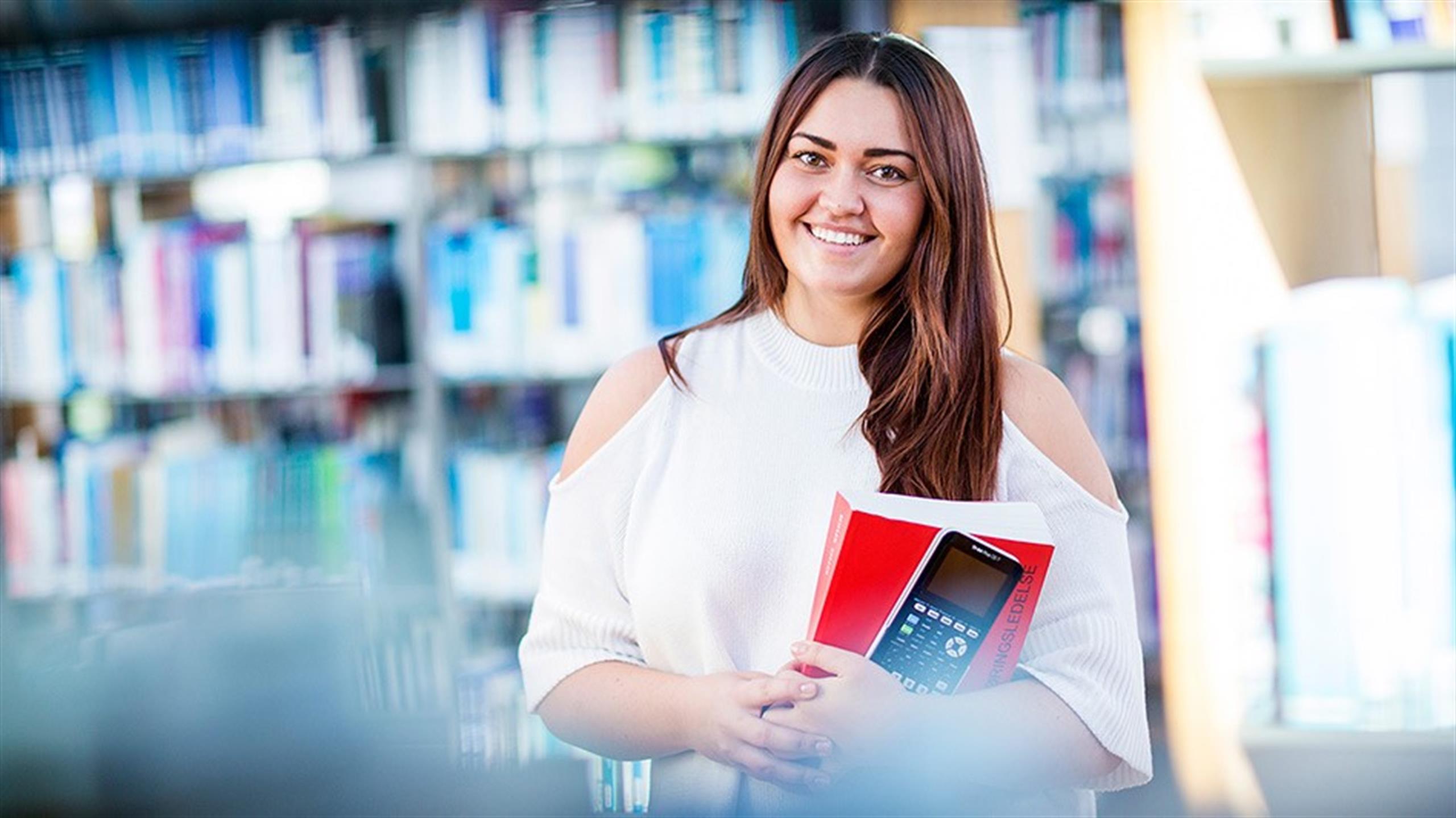Kvinnelig student med bok og kalkulator i hånda