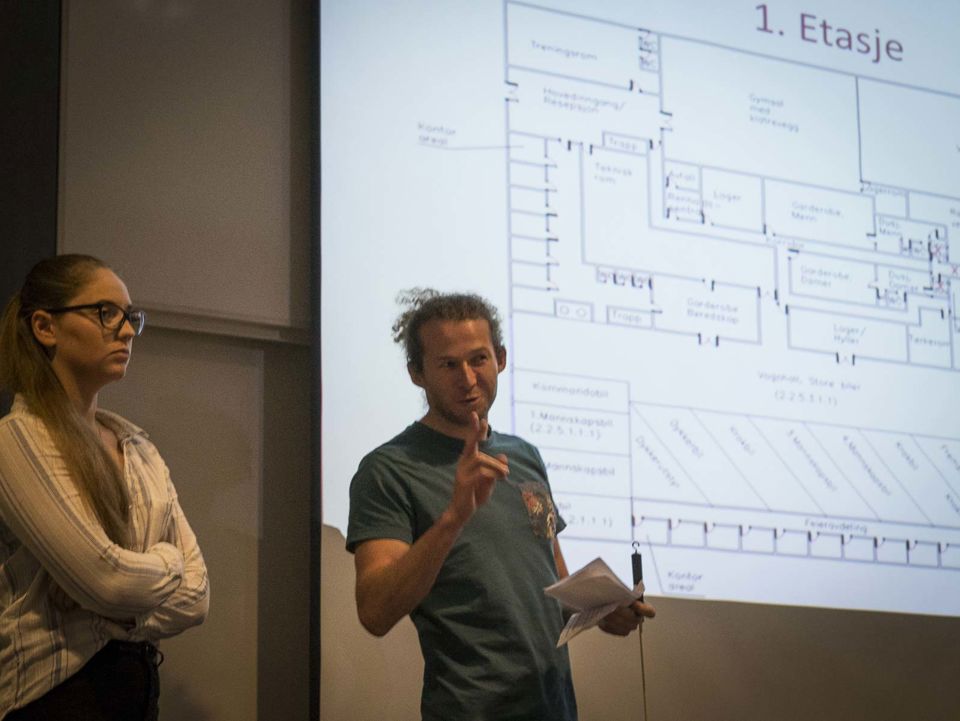 To studenter foreleser med slide i bakgrunnen.