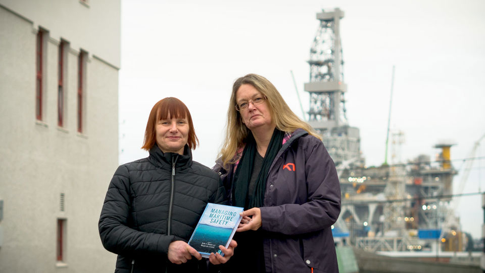 To kvinner oppstilt ute med bok i hendene