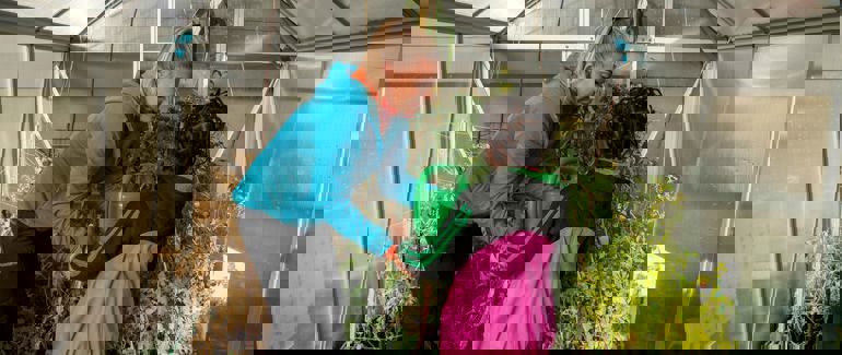 Praksisstudent i barnehage saman med barn i drivhus