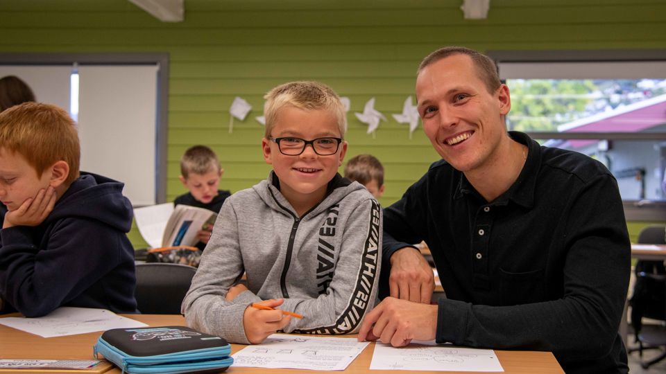 Student i praksis på barneskulen saman med elev.