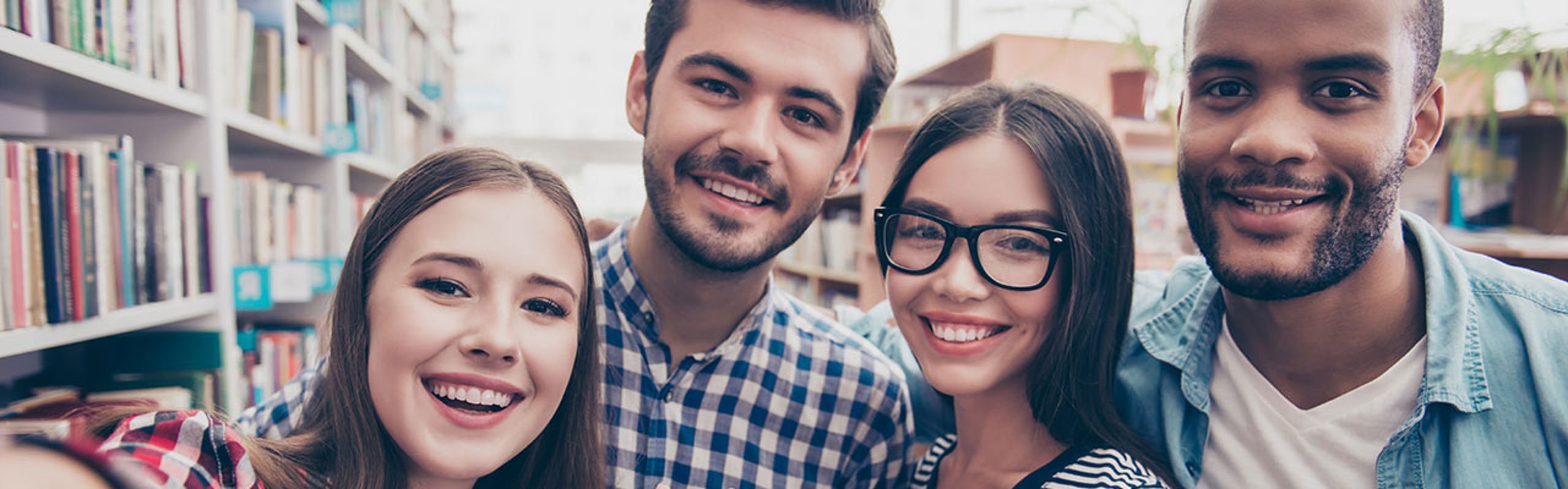 Fire studentar tar selfie på bibliotek.