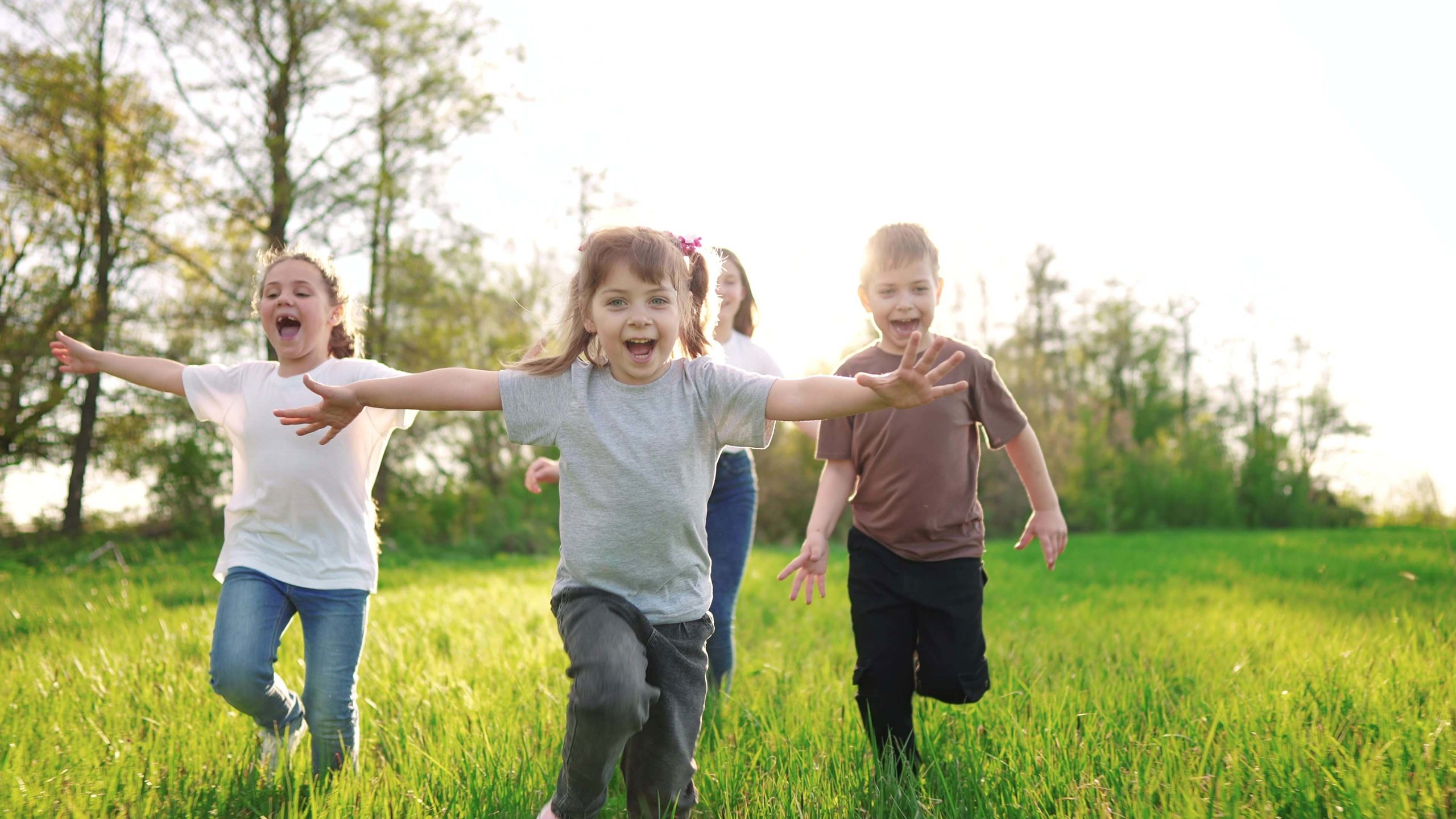Smilende barn løper på en gressplen. 