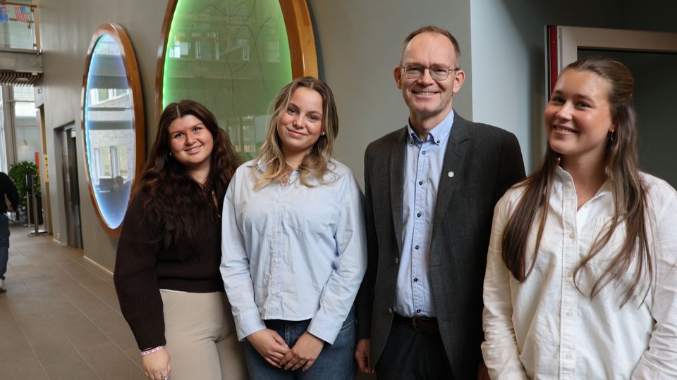Tre unge studentar står i lag med kunnskapsminsteren og smiler mot fotografen