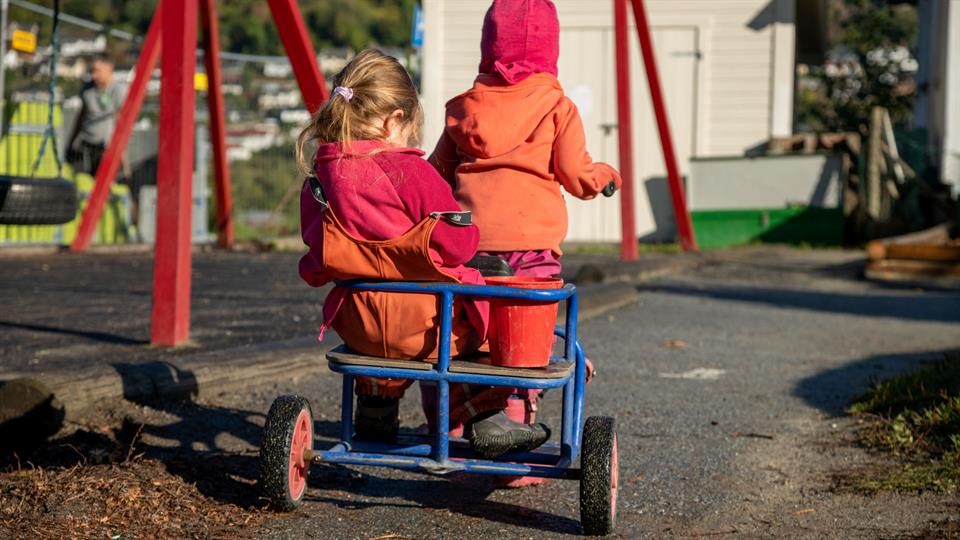 To barnehagebarn på trehjulssykkel.