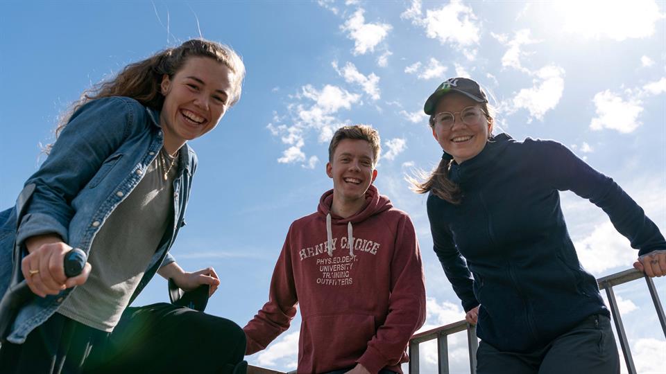 Tre studenter som smiler