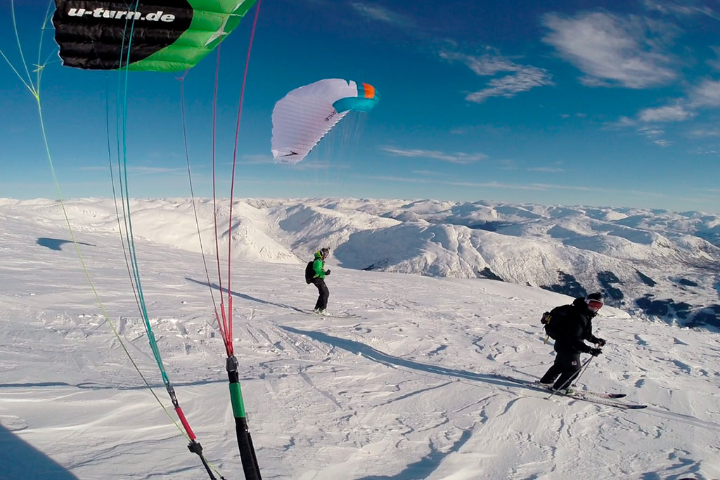 Freeridingskøyrarar ned snøkledd fjellside.