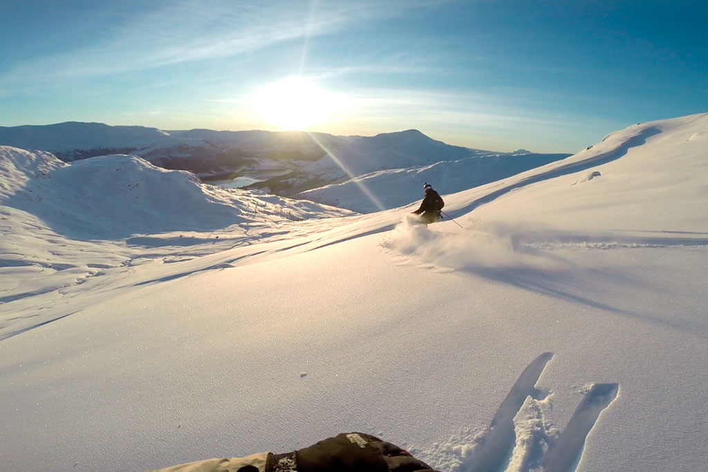 Skiløpar ned snøkledd fjellside.