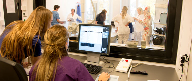 radiografistudentar ser på datamaskin i kontrollrom.